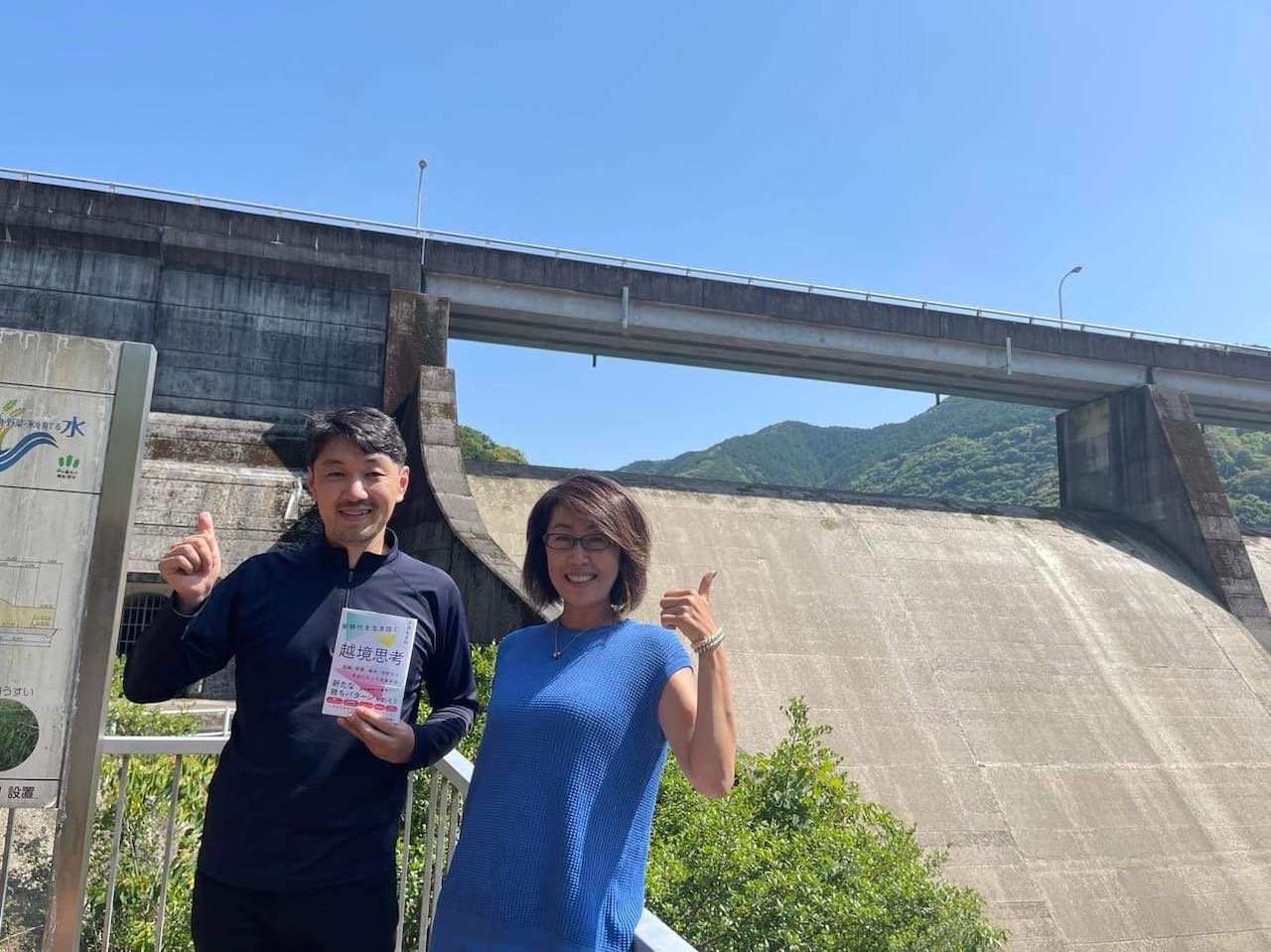 島ノ瀬ダムをバックに微笑む沢渡あまねさんと島田由香さん